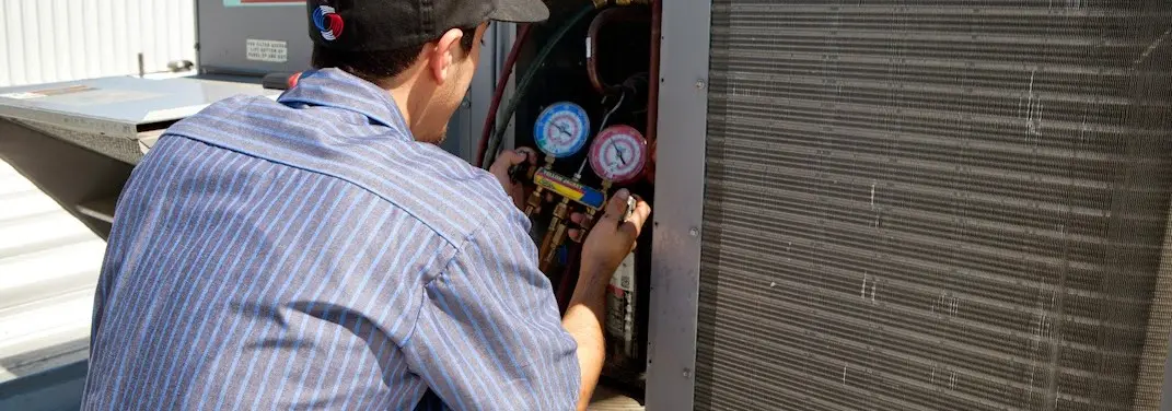 HVAC technician servicing a condenser unit in Oneida