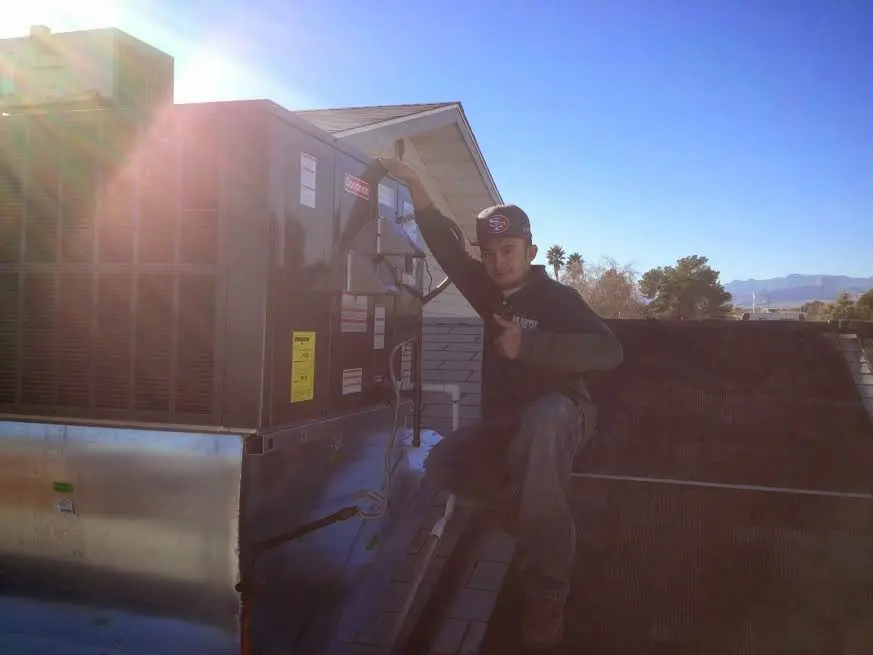 HVAC technician performing AC Tune-Up on a rooftop unit in Oneida